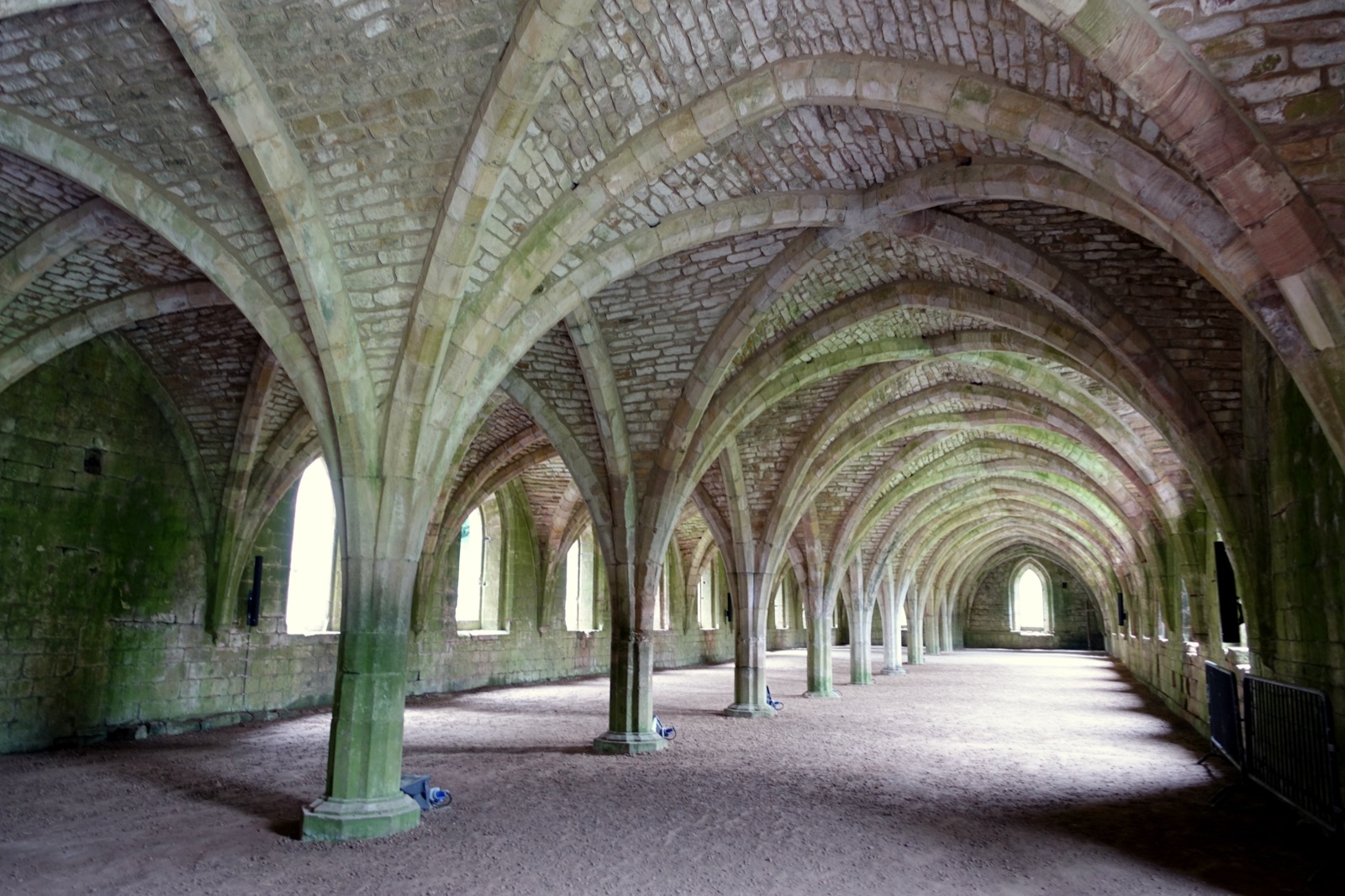 Fountains Abbey corridor, stone columns and vaults stretching into the distance